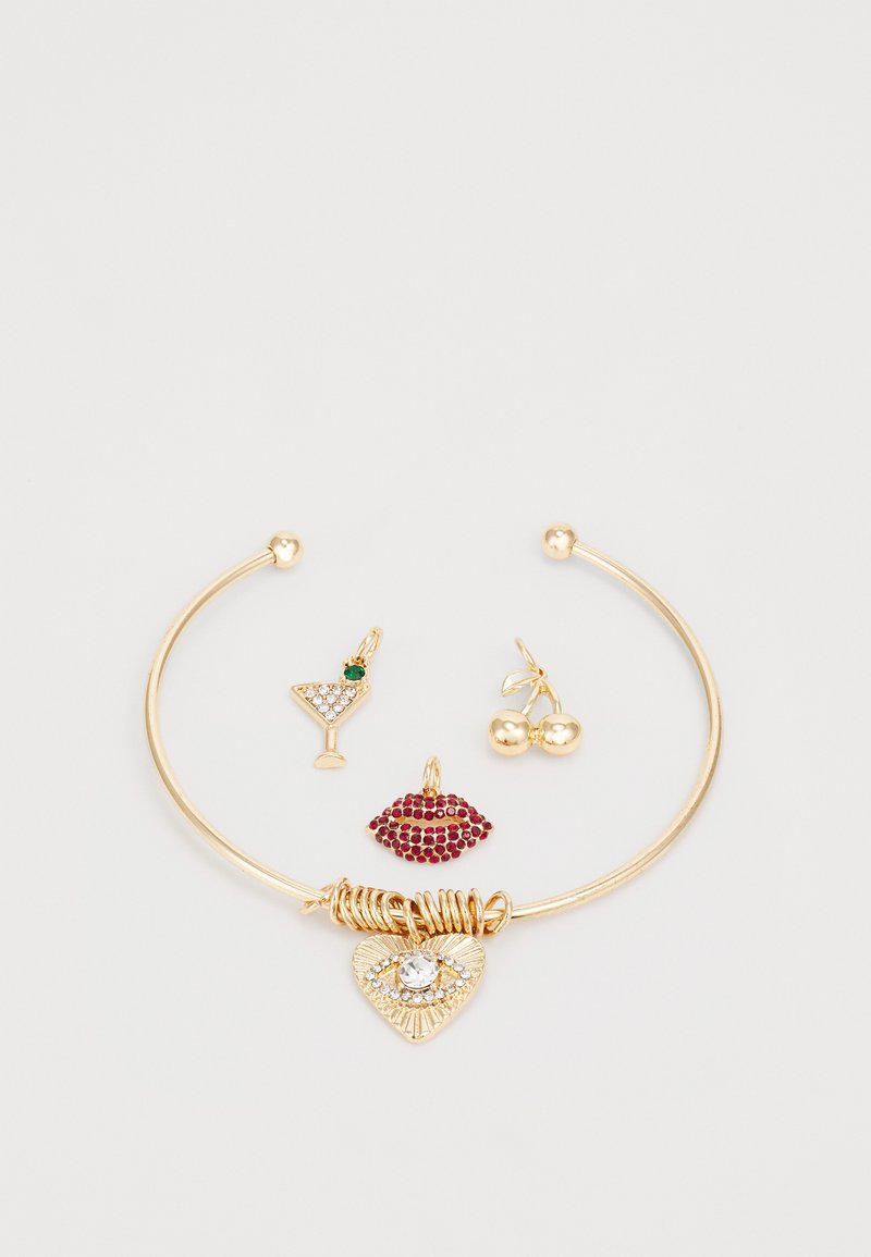Pulsera de oro con tres charms: un corazón con un cristal, labios rojos y una copa de cóctel con acento verde y cerezas. Acabado suave.