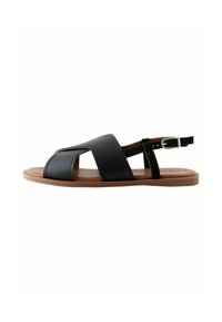 Sandal in pelle nera con suola piatta, punta aperta e fasce incrociate. Presenta una cinturino per la caviglia con una fibbia argentata e suola marrone.
