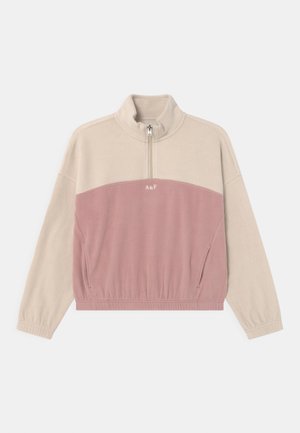 Half-zip pullover in beige en lichtroze fleece. Voorzien van een hoge kraag, elastische tailleband, zijzakken en een geborduurd logo aan de voorkant.