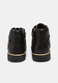 Chaussures noires en cuir à chevilles avec un motif matelassé texturé, des détails dorés sur la semelle, et un accent décoratif en sequins noirs.