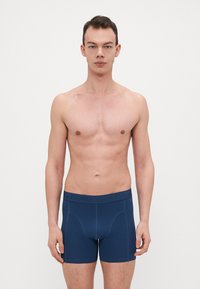 Sötétkék boxeralsó, elasztikus derékrésszel, dombornyomott logóval, sima textúrával és testhezálló kialakítással.