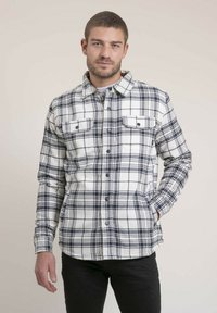 Chemise à carreaux blanche et marine, avec deux poches poitrine, un devant boutonné et une coupe décontractée. Fabriquée dans un matériau doux et texturé.