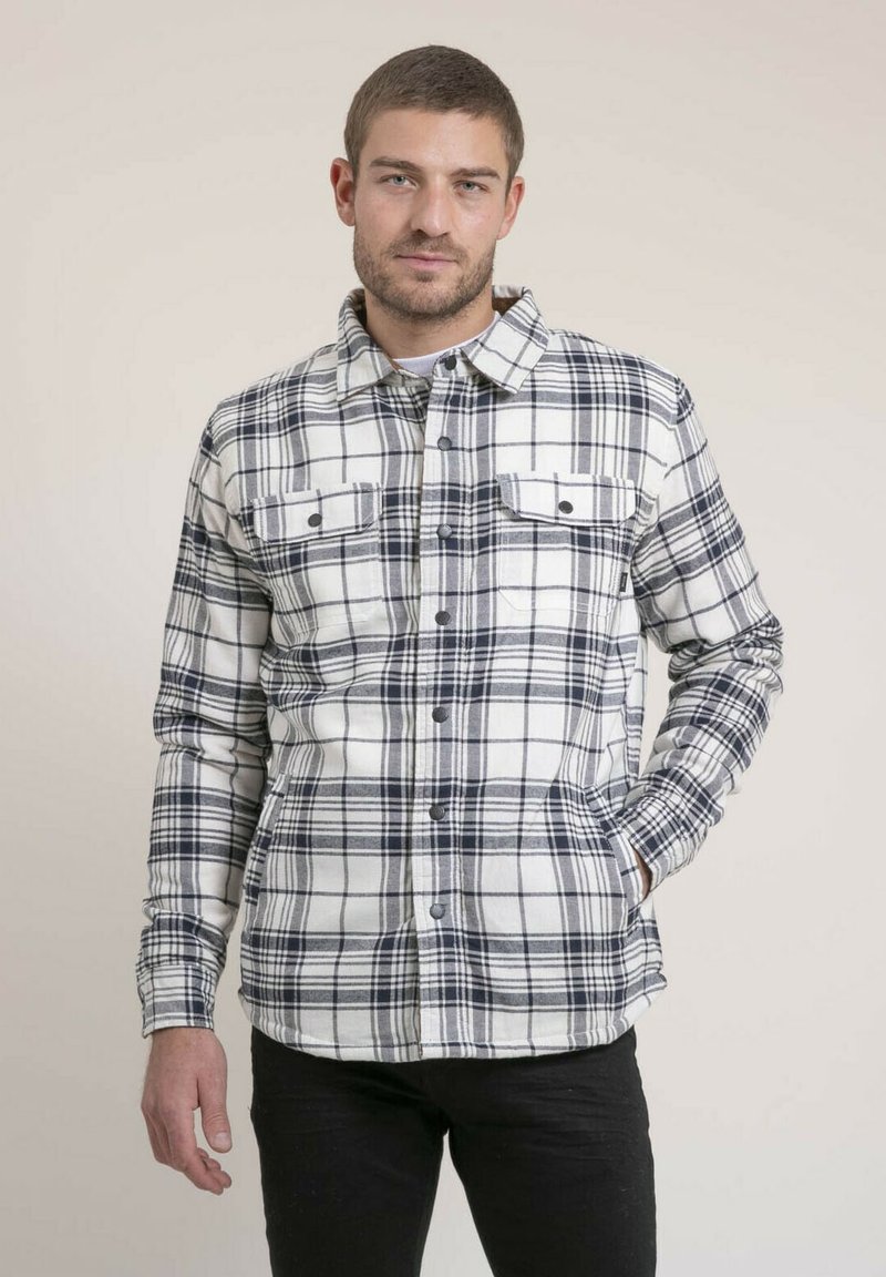 Chemise à carreaux blanche et marine, avec deux poches poitrine, un devant boutonné et une coupe décontractée. Fabriquée dans un matériau doux et texturé.