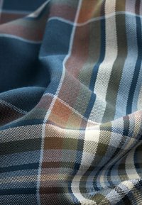 Tejido tejido con un patrón de tartán en azul oscuro, verde y marrón, con rayas alternas y una superficie texturizada.