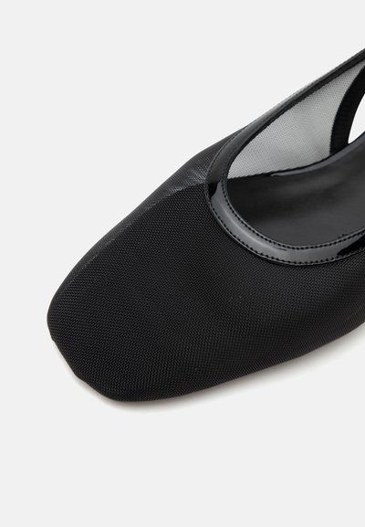 Chaussure plate en tissu noir texturé avec un bout carré et une bordure brillante autour de l'ouverture, vue d'un angle latéral supérieur.