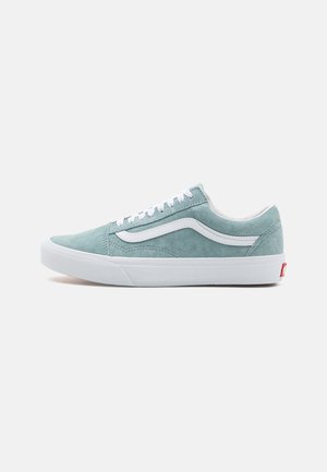 Zapatillas de ante azul claro con cordones y detalles en blanco. Presentan una franja lateral blanca y un logotipo rojo en el talón. Suela de goma plana.