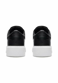 Black leather shoes with textured surface, low design, and white platform sole. Back view shows subtle branding and rounded heels.