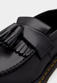 Crne kožne mokasinke s sjajnim završetkom, ukrašene resama, sašivene detalje i kontrastnim žutim potplatom.