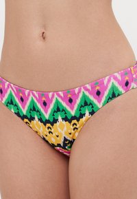 Bikiniunderdele i et farverigt mønster med pink, grønne, gule og sorte geometriske former. Fremstillet af glat, strækbart stof.