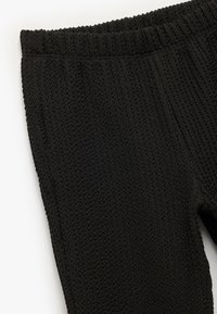Svarta texturerade leggings med ett ribbat stickmönster och ett elastiskt midjeband för ökad komfort och flexibilitet.