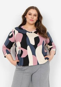 Top dai colori vivaci con forme astratte nei toni di rosa, nero e crema, con scollatura a V e maniche a tre quarti. Tessuto morbido al tatto.