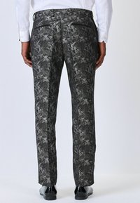 Black and gray patterned trousers with a floral design, featuring a straight cut and two back pockets, paired with sleek black shoes.