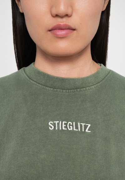 Olivovozelená mikina s okrúhlym výstrihom a bielym vyšitým textom "STIEGLITZ" na hrudi. Mäkký materiál, ležérny dizajn.
