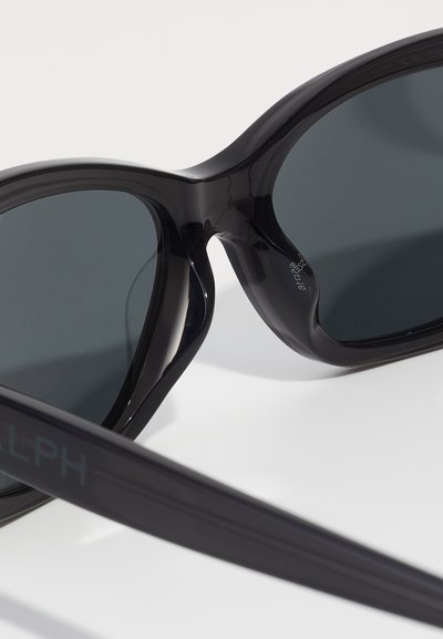 Czarne, oversize okulary przeciwsłoneczne z półprzezroczystą oprawą i ciemnymi szkłami. Charakteryzują się eleganckimi liniami i matowym wykończeniem na zausznikach.