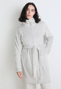 Rochie de dormit căptușită de culoare gri deschis, cu guler înalt, fermoar complet, cordon și buzunare laterale. Textură moale cu un model în diamant pe toată suprafața.