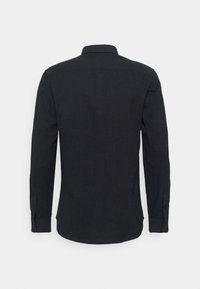 Camicia nera a maniche lunghe con colletto a camicia, polsi singoli e tessuto testurizzato. Il retro presenta un orlo curvo e nessun motivo visibile.