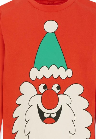 La chemise rouge à manches longues présente un Santa en dessin animé avec un chapeau vert et une barbe blanche. Le design comprend des couleurs vives et des formes simples.