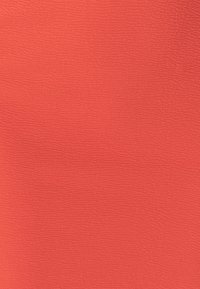 Koralfarvet tekstureret stof med et bølget mønster, der har en blød overflade og ensartet farve. Ingen synlige mønstre eller yderligere detaljer.