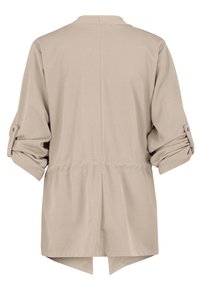 Beige lange mouw jas met opgerolde mouwen, getailleerde taille en asymmetrische zoom, van achteren getoond tegen een witte achtergrond.