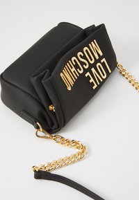 Black rectangular crossbody bag with gold chain strap and gold "LOVE MOSCHINO" lettering on the front flap.