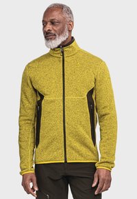 Fleecejacke in leuchtendem Gelb mit strukturiertem Finish. Schwarze Akzente an den Seiten und mit Reißverschlüssen ausgestattet. Hoher Kragen und durchgehender Reißverschluss.