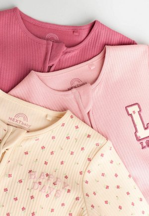 Drie babytops in roze en crème: geribbelde stof, ronde hals en drukknoopsluitingen. Eén heeft een bloemenpatroon en borduursel met de tekst "HAPPY DAYS."