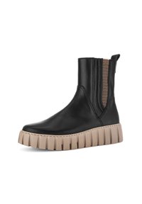Bottine en cuir noir avec semelle épaisse beige à crête et panneaux élastiques marron sur les côtés pour un enfilage facile.