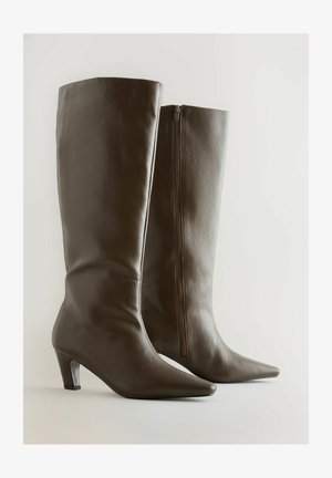 Pruunid nahast põlvekõrgused saapad, millel on terav varvas ja kitsas konts. Omavad külgset tõmblukk ja siledat tekstuuri.