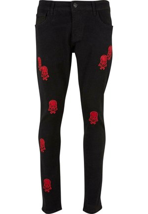 Jean skinny noir en denim, dotés d'une broderie rouge de skull et os croisés sur le devant pour un détail et un intérêt visuel.