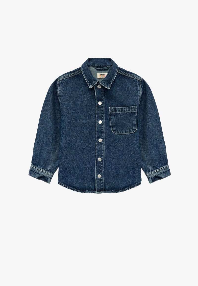 Tummansininen farkkupaita napilla. Ominaisuuksina terävä kaulus, pitkät hihat ja yksi rintatasku. Hopeansävyiset napit.