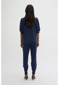 Navy blue loungewear set featuring a short-sleeve top with puffed sleeves and matching tapered pants, made from soft, textured fabric.