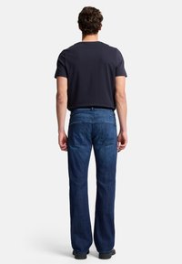 Mörkblå denimjeans med raka ben, fem fickor och en standard midja. Matchad med en svart t-shirt med kort ärm.