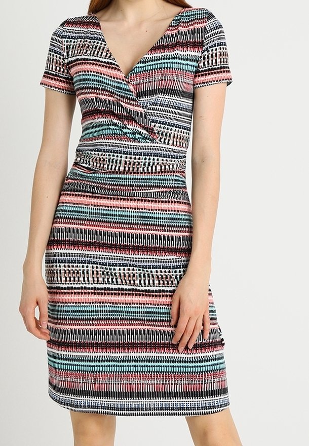 Femme portant une robe courte à manches courtes, col en V, longueur genou, avec des rayures horizontales multicolores en motifs noir, blanc, rose et bleu sarcelle.