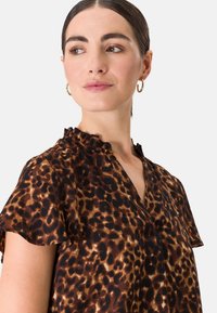 Luipaardprint blouse met een geraffineerde halslijn. Gemaakt van zachte stof in bruin en zwarte tinten, met korte mouwen en een losse pasvorm.