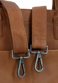 Braune Ledertragriemen mit silbernen Metallbeschlägen, einem strukturierten Finish und kontrastierenden Nähdetails.