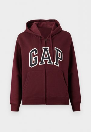 Hanorac bordo cu fermoar, buzunare frontale, glugă cu șnur și inscripție mare "GAP" albă și neagră pe piept.