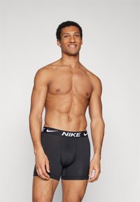 Black Nike boxer briefs featuring a white branded waistband. The fabric appears smooth with a fitted design, suitable for active wear.