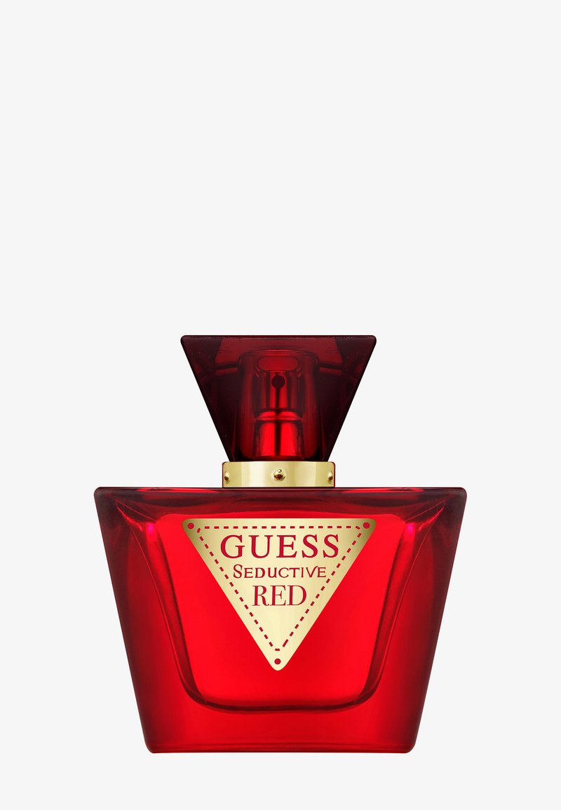 Bottiglia di profumo in vetro rosso con design triangolare, dettagli dorati e un'etichetta con il logo ben visibile che recita "GUESS Seductive RED."
