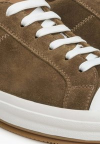 Brązowe zamszowe sneakersy z białymi sznurowadłami, teksturowaną boczną wstawką i gumową podeszwą. Posiadają gładkie akcenty i detale w szwach.