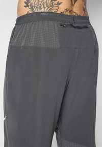 Nike löpshorts i grått tyg, med en texturerad midja som har en ficka med dragkedja och en slät, lätt textur genom hela shortsen.