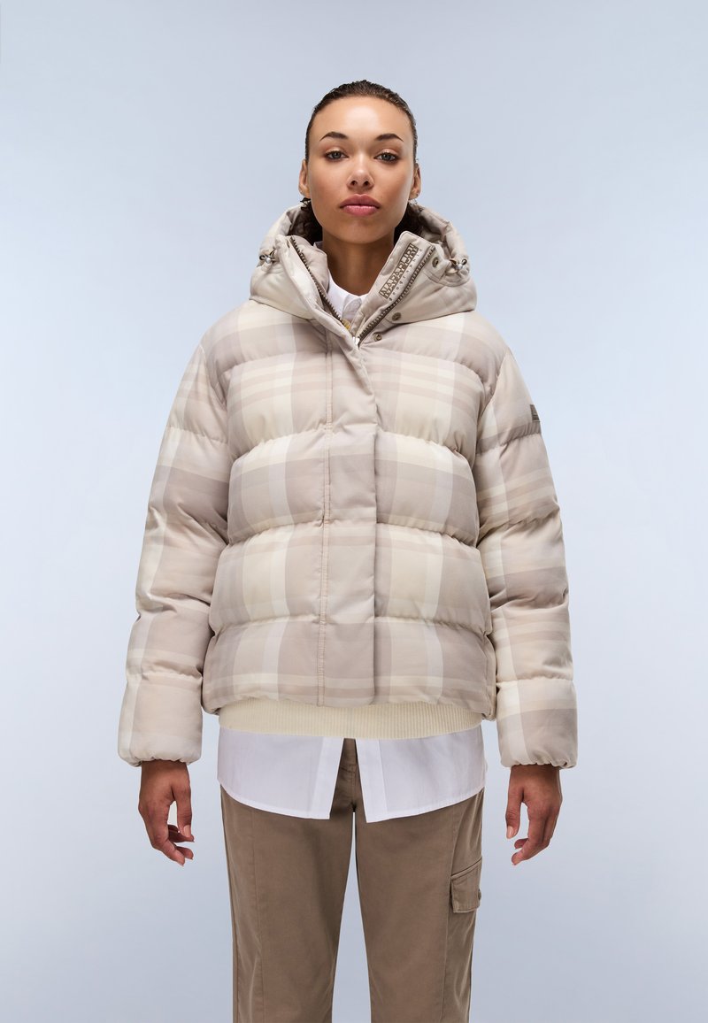 Beige rutigt pufferjacka med huva, med en texturerad ytterlager och ribbade ärmslut, bärs över en vit skjorta och beiga byxor.