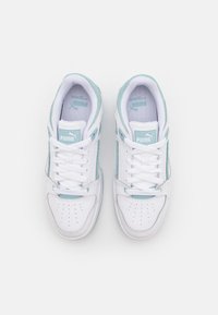 Valkoiset tennarit vaaleansinisin yksityiskohdin, joissa on sileä nahkapinta, rei'itetty kärki ja litteät nauhat. Puma-logo näkyy kielekkeessä.