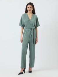 Mintgrønn plissert jumpsuit med omslagdesign, korte vide ermer, belted liv og rett ben-silhuett. Svarte høye hæler.