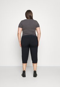 Szary top z krótkim rękawem w połączeniu z granatowymi spodenkami o długości do kostek, z elastycznym pasem i czarnymi botkami, zdjęcie z tyłu.