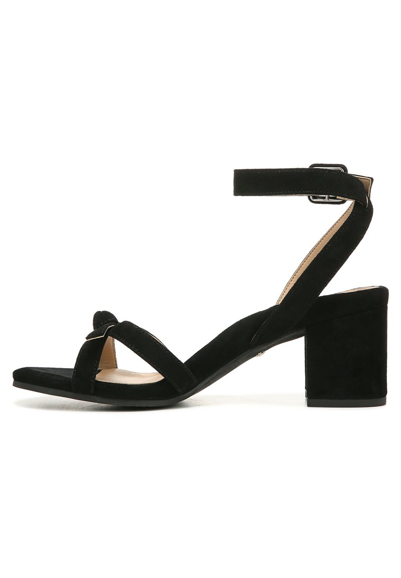 Black suede sandal featuring a wide strap design, a knotted detail at the front, and a block heel for stability. Adjustable ankle strap included.
