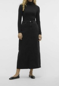 Černá denimová maxi sukně se rovný střihem, předním rozparkem a středně vysokým pasem. Kombinována s černým topem s dlouhým rukávem a černými balerínami.