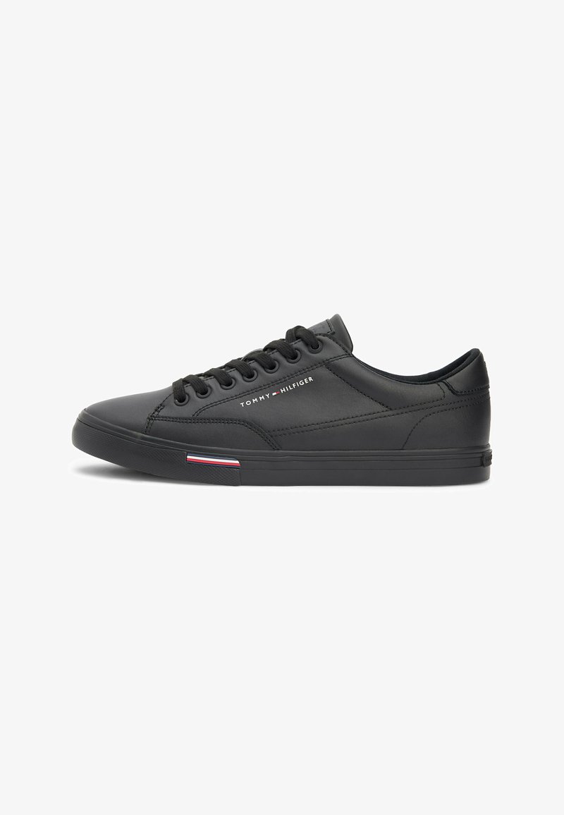 Baskets basses en cuir noir avec lacets noirs, logo Tommy Hilfiger sur le côté et détail de rayures rouge, blanc et bleu sur la semelle.