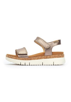 Sandales à plateforme en liège avec des brides en bronze métallisé, des fermetures velcro réglables et une semelle intérieure rembourrée pour le confort. Semelle en caoutchouc blanche.
