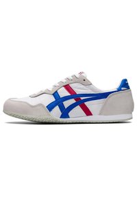 Hvid sneakers med grå ruskindsdetaljer, blå og røde syntetiske striber, flade snørebånd og struktureret gummi sål. Klassisk design med sporty elementer.