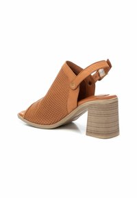 Scarpe con tacco aperte beige con un design perforato, cinturino alla caviglia regolabile e tacco a blocco testurizzato.